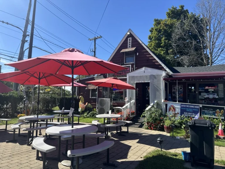 Outdoor patio tables beneath red umbrellas outside Rooster's Wings & Brew in Mohegan Lake, NY.