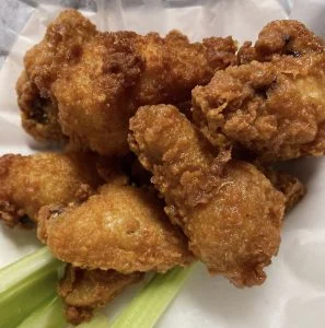 Golden breaded Southern Fried wings with celery at Rooster's Wings & Brew.
