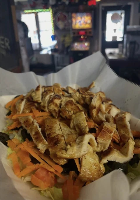 Grilled chicken salad topped with sliced chicken and shredded cheese at Rooster's Wings & Brew.