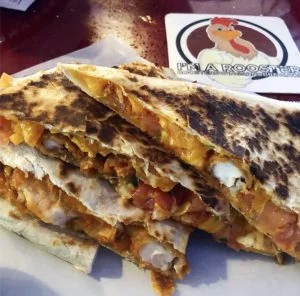 Stacked toasted quesadilla wedges with melted cheese, tomato and green vegetables.
