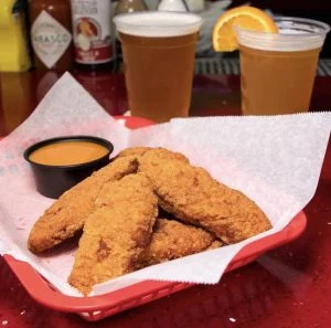 Chicken tenders with dipping sauce at Rooster's Wings & Brew.