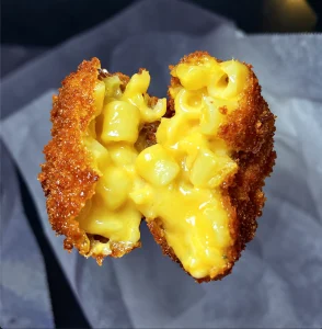 Homemade mac and cheese ball cut open to show the cheesy macaroni filling.