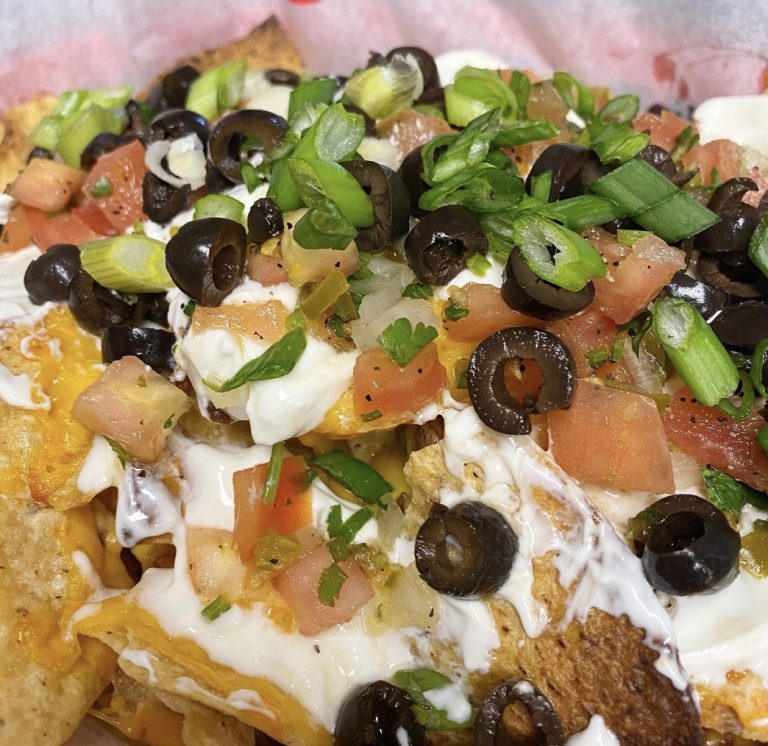 Loaded nachos with melted cheese, sour cream, tomatoes, black olives and green onions at Rooster's Wings & Brew